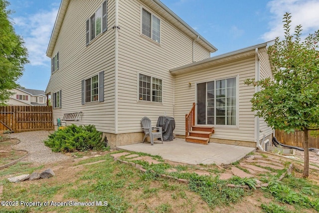 rear view of property with entry steps, a patio, and fence