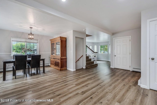 dining space featuring stairs, plenty of natural light, wood finished floors, and a baseboard radiator