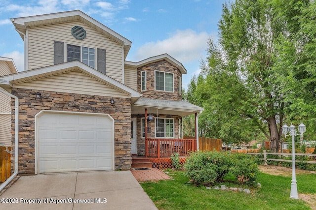 traditional-style house with fence, driveway, a porch, an attached garage, and stone siding
