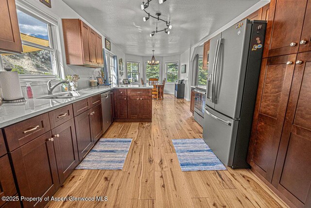 1321 Lecuyer Dr, Craig, CO 81625 - kitchen featuring stainless steel appliances, light wood finished floors, a peninsula, a chandelier, and a sink