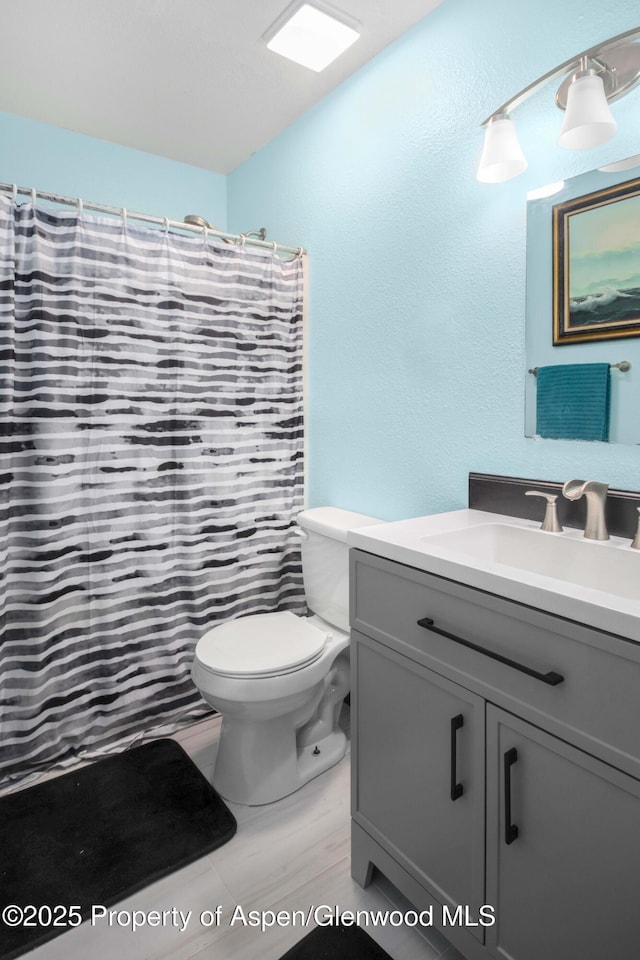 bathroom with vanity, a shower with shower curtain, and toilet