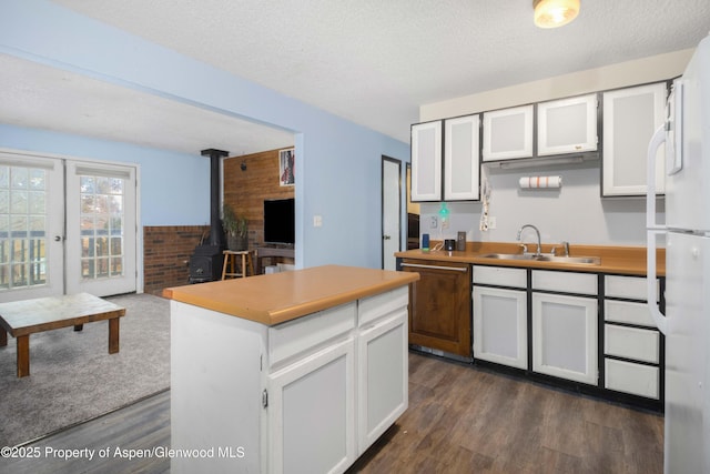 kitchen with sink, a wood stove, white cabinets, and a kitchen island