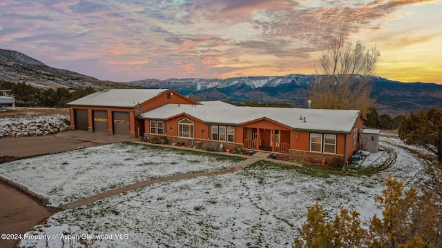 single story home with a garage, a mountain view, and a porch