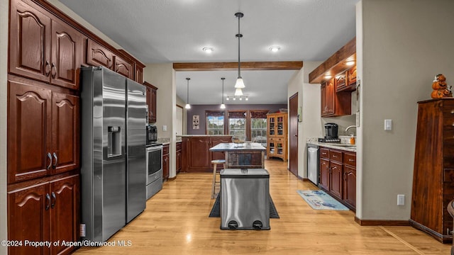 kitchen with hanging light fixtures, appliances with stainless steel finishes, a kitchen breakfast bar, a kitchen island, and beam ceiling