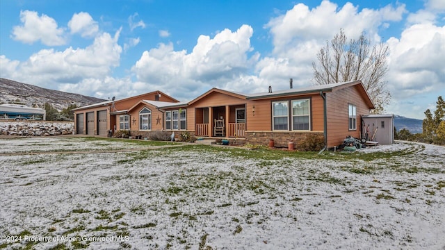 single story home with a garage, a mountain view, and covered porch