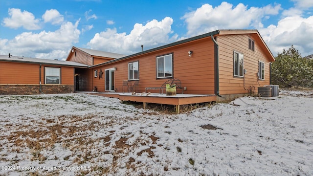 snow covered house with central AC and a deck