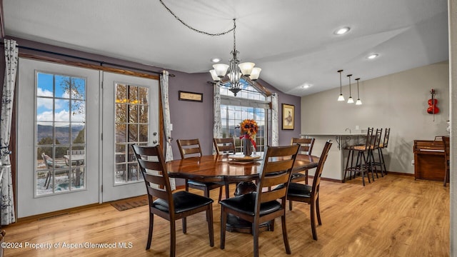 dining space with vaulted ceiling, an inviting chandelier, and light hardwood / wood-style floors