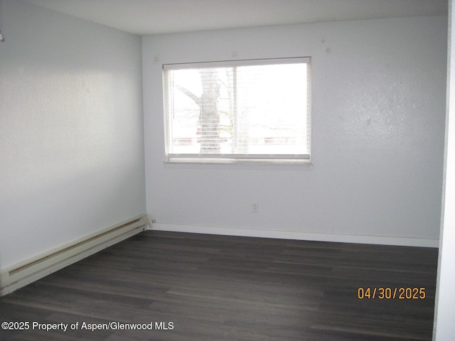 empty room featuring baseboards, baseboard heating, and dark wood finished floors