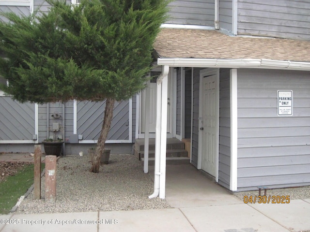 property entrance featuring roof with shingles