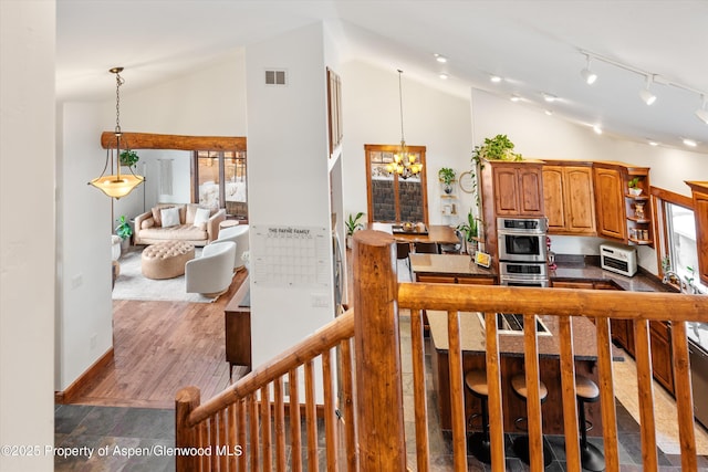 kitchen with hanging light fixtures, an inviting chandelier, high vaulted ceiling, and dark hardwood / wood-style floors