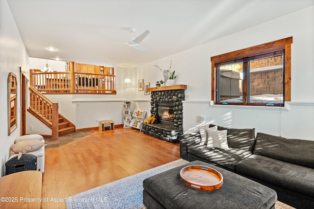 living room with a fireplace, ceiling fan, and light hardwood / wood-style flooring