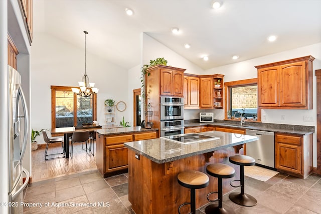 kitchen with stainless steel appliances, hanging light fixtures, a breakfast bar, a kitchen island, and an inviting chandelier