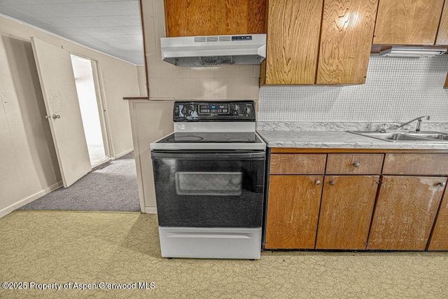 415 Tucker St, Craig, CO 81625 - kitchen featuring electric range oven, under cabinet range hood, a sink, light countertops, and brown cabinetry