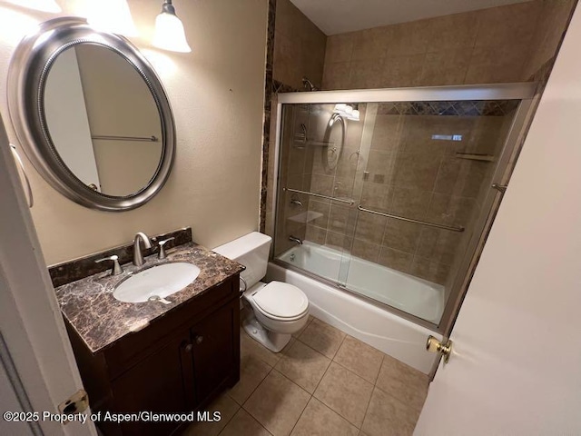 full bathroom featuring tile patterned flooring, bath / shower combo with glass door, vanity, and toilet