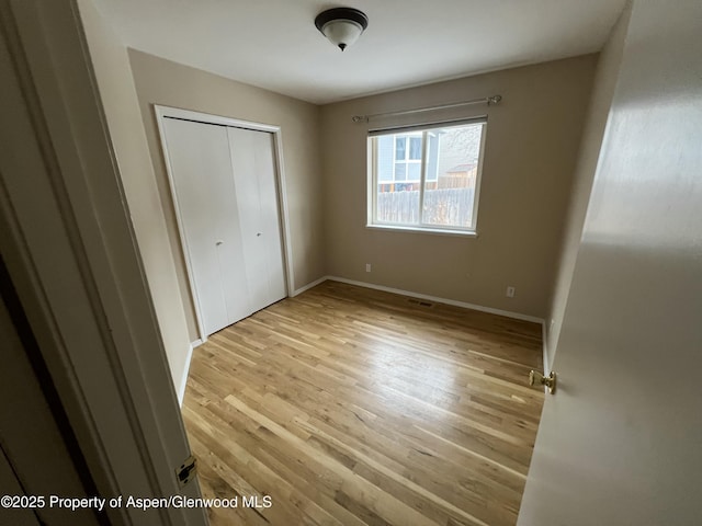 unfurnished bedroom with a closet and light wood-type flooring