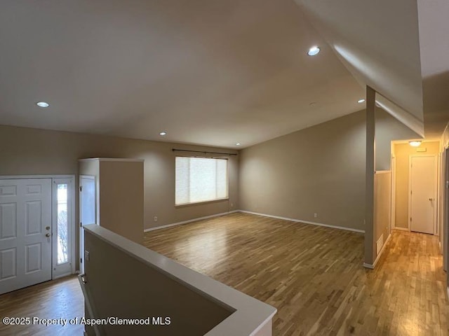 entrance foyer featuring wood-type flooring and vaulted ceiling