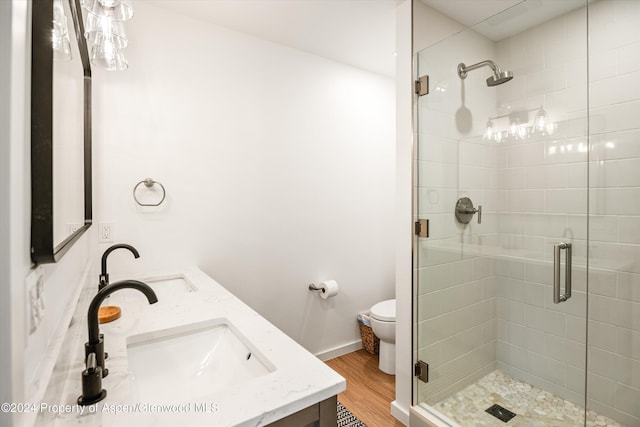 bathroom with hardwood / wood-style floors, vanity, toilet, and a shower with shower door