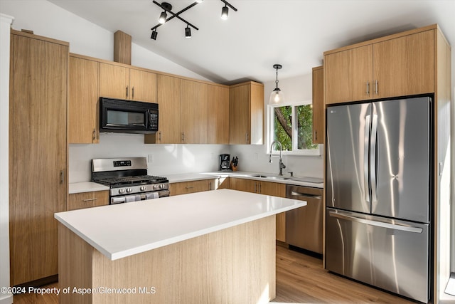 kitchen featuring hanging light fixtures, stainless steel appliances, light hardwood / wood-style floors, vaulted ceiling, and a kitchen island