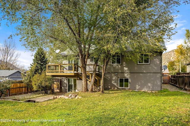 rear view of house with a lawn and a wooden deck