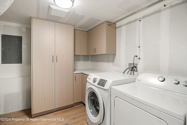 laundry area featuring electric panel, cabinets, light wood-type flooring, and independent washer and dryer