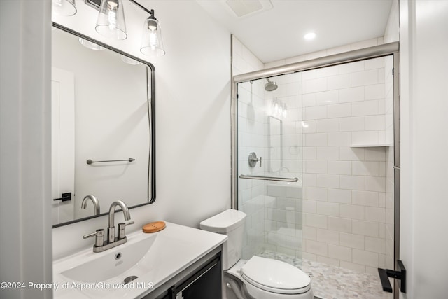 bathroom featuring vanity, toilet, and a shower with door