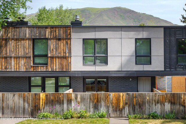 250 S Original St Unit B, Aspen, CO 81611 - rear view of property with a fenced front yard, brick siding, a mountain view, a chimney, and stucco siding