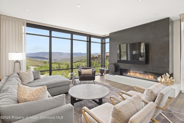 77 Wood Rd Unit 507-13, Snowmass Village, CO 81615 - living room featuring a wall of windows, wood finished floors, a glass covered fireplace, and recessed lighting