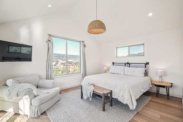 bedroom featuring a mountain view, high vaulted ceiling, and light hardwood / wood-style flooring