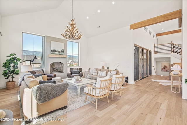 living room with french doors, a towering ceiling, a chandelier, and light wood-type flooring