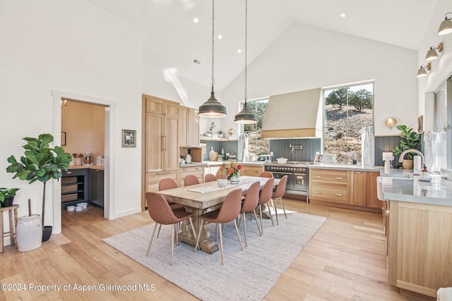 dining room featuring light hardwood / wood-style flooring, high vaulted ceiling, and sink