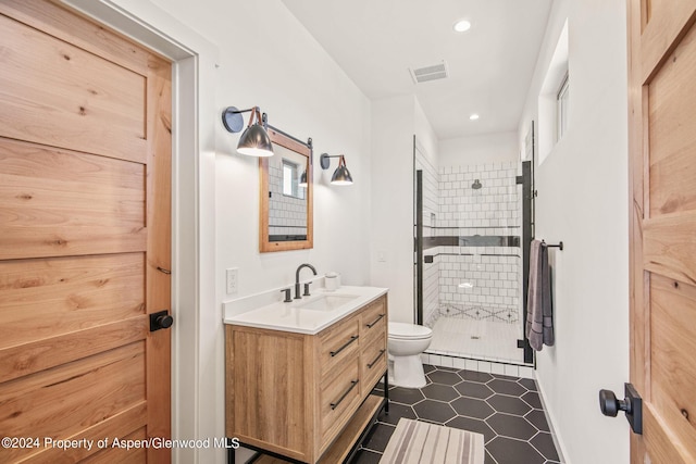 bathroom featuring tile patterned floors, toilet, vanity, and walk in shower