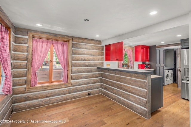 kitchen featuring kitchen peninsula, stainless steel fridge, light wood-type flooring, and rustic walls