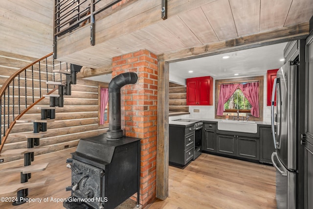 kitchen with sink, light hardwood / wood-style flooring, gray cabinets, log walls, and stainless steel appliances