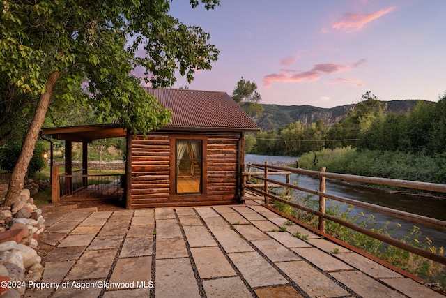 deck at dusk featuring a water and mountain view