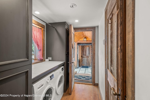 clothes washing area with independent washer and dryer and light hardwood / wood-style floors