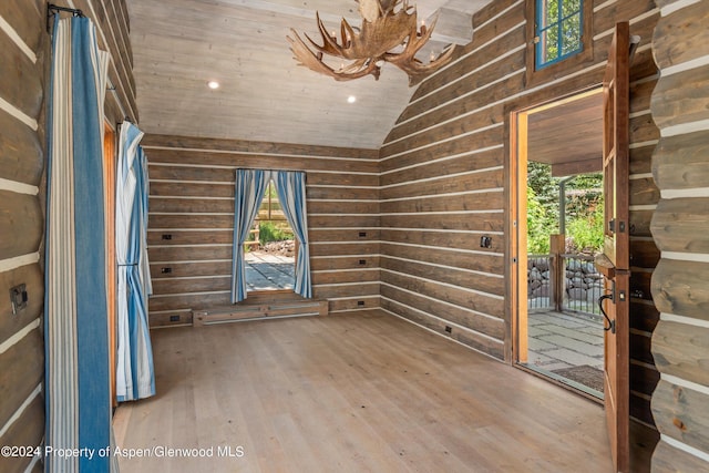 unfurnished room with wood-type flooring, lofted ceiling, wooden walls, and wood ceiling