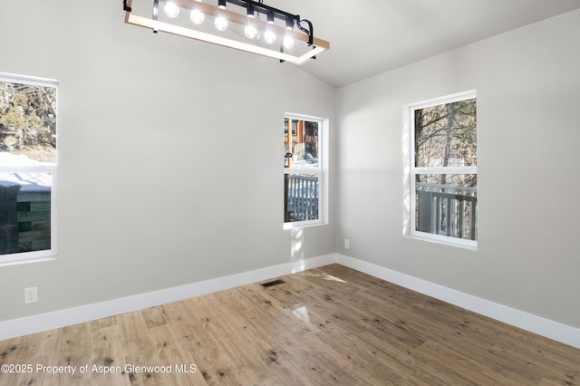 spare room featuring hardwood / wood-style flooring and vaulted ceiling