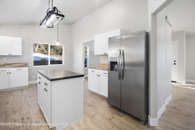 kitchen with stainless steel fridge, hanging light fixtures, a center island, white cabinets, and light wood-type flooring