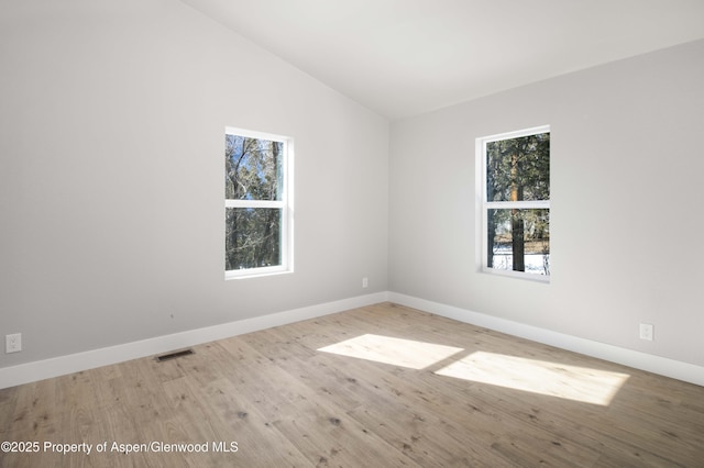 spare room featuring lofted ceiling and light wood-type flooring