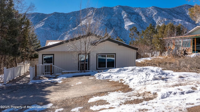 snow covered rear of property featuring a mountain view