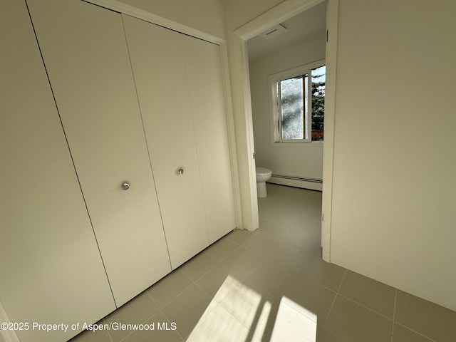 interior space featuring ensuite bathroom, light tile patterned floors, and a baseboard heating unit