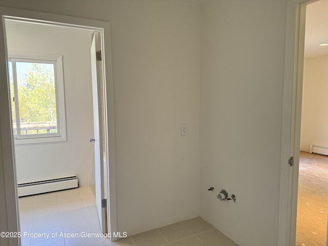 clothes washing area with light tile patterned floors and baseboard heating