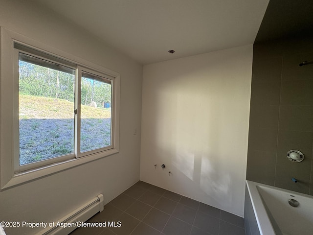 unfurnished room featuring dark tile patterned floors and baseboard heating