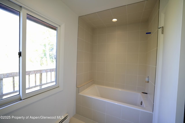 bathroom with tiled shower / bath and a baseboard heating unit