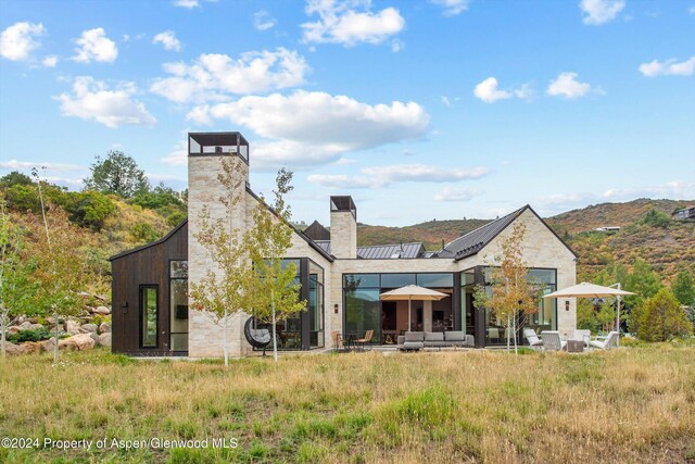 back of house with a mountain view, solar panels, an outdoor hangout area, and a patio