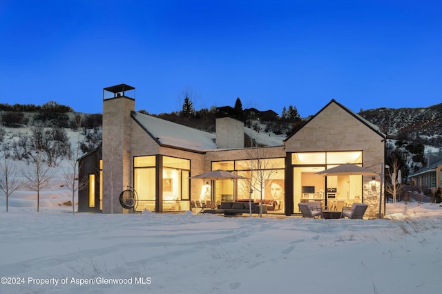 snow covered back of property with outdoor lounge area