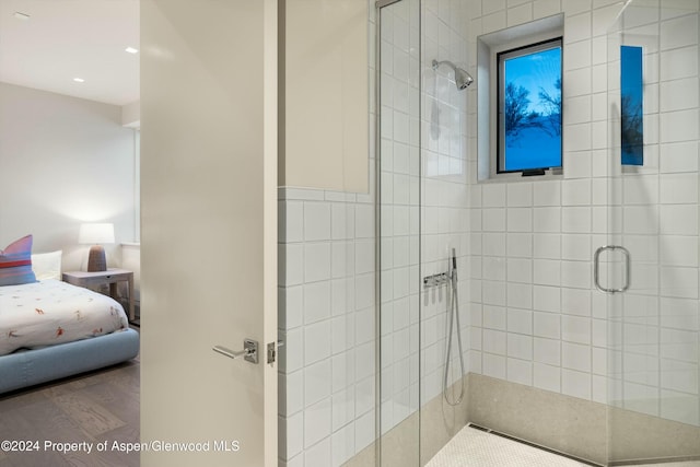 bathroom with a shower with door and wood-type flooring