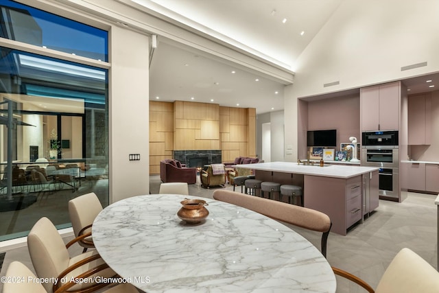 dining area featuring a fireplace and high vaulted ceiling