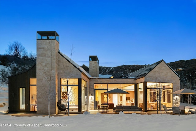 snow covered back of property with an outdoor living space