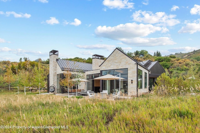 387 Branding Ln, Snowmass Village, CO 81615 - back of house featuring a standing seam roof, a metal roof, a chimney, and stone siding